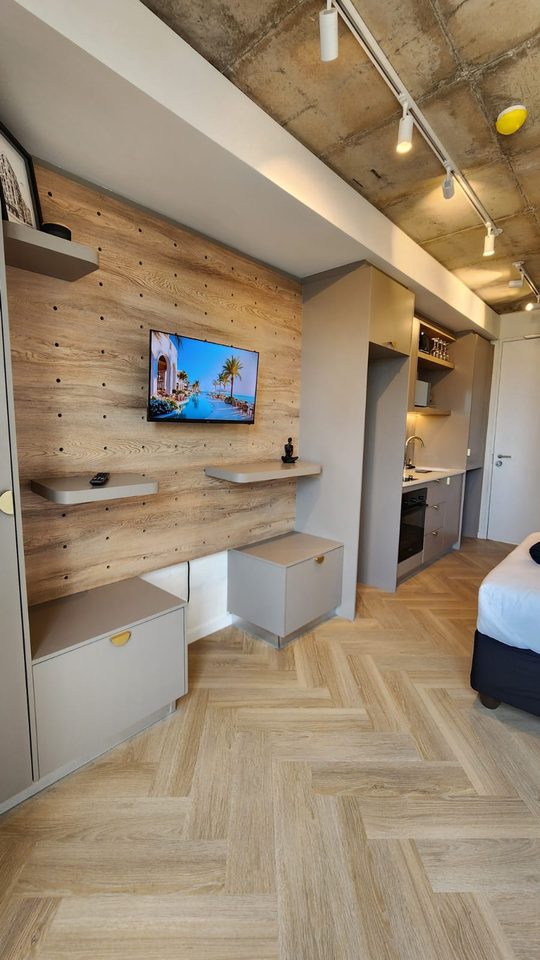 The studio from the door: TV wall, bed and herringbone floor