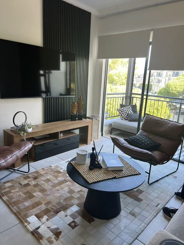 Lounge with TV, leather chairs and the balcony door