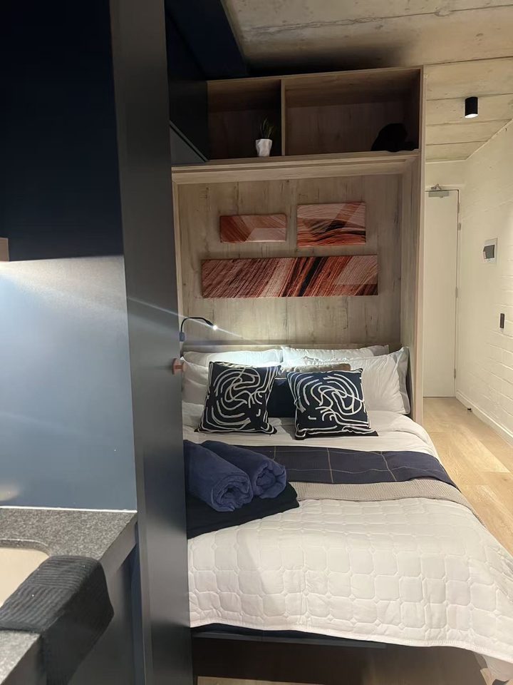 Wall bed folded down and made up with navy cushions